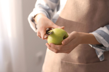 Woman peeling ripe apple, closeup
