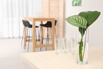 Vase with tropical leaves on table indoors. Interior design element