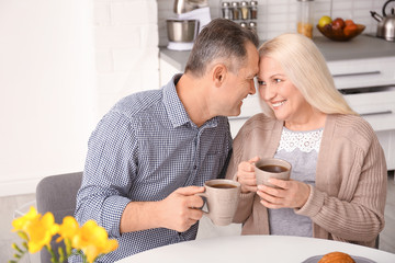 Happy senior couple drinking coffee together at home