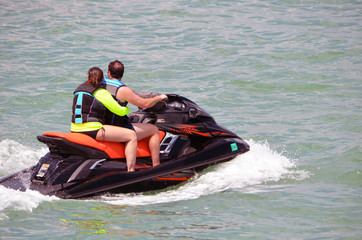 Fototapeta na wymiar Young couple riding tandem on a jet ski on the florida intra-coastal waterway off Miami Beach.