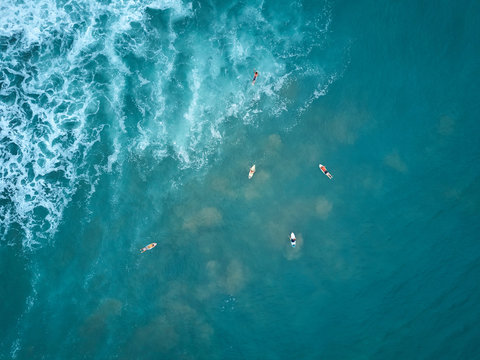 Surfers swim to big wave