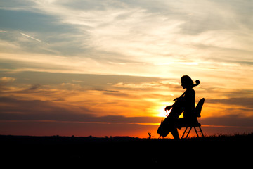 Fototapeta na wymiar woman playing cello music in a sunset 
