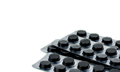 Activated charcoal tablets pills in blister pack isolated on white background with copy space for text. Black round pills for treatment poisoning from take drug overdose