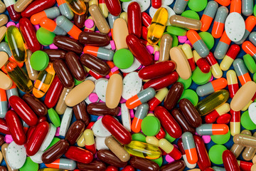 Pile of colorful tablets and capsule pills. Full frame of medicine, vitamins and supplements. Top view many of pills background. Drug, vitamin, supplement and herbal medicine interaction concept.