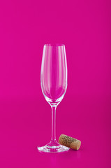 Wine glass with cork on pink background