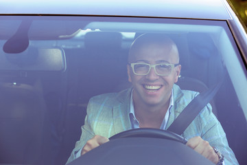 Handsome business man smiling looking out of his new car window