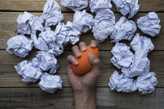 Hand of a woman squeezing a stress ball with crumpled paper