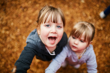 two young sisters looking up on camera on playground silly face