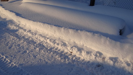 Obraz premium Traces of heavy machinery on a snowy road in the rays of the rising sun.