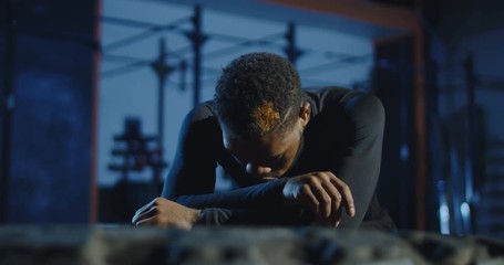 Muscular African-American sportsman working out in gym and looking tired while training. Slowmotion shot on Red cinema camera.