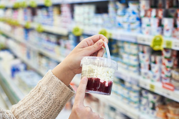 Buyer reading cottage cheese with jam in grocery
