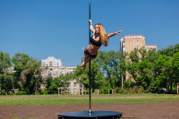 Fit attractive girl dancing near portable pole at summer day © Smile