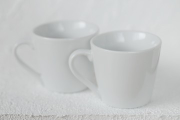Fototapeta premium tableware mockup. Minimalist cup Mockup. Two white cups on a white relief background. White cup on white background. copy space