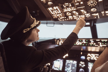 Female pilot the captain of the plane prepares for take-off in the plane cockpit. Girl pilot in uniform flying craft plane in the sky - obrazy, fototapety, plakaty