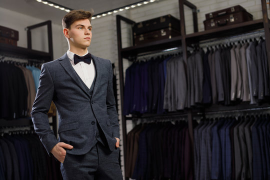 Businessman in classic vest against row of suits in shop. A young stylish man in a jacket. It is in the showroom, trying on clothes, posing. Advertising photo
