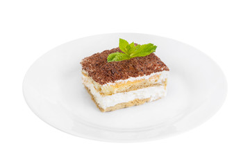 Tiramisu with mint on a white plate isolated white