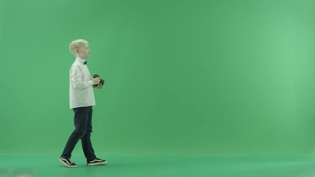 The child is walking and taking photos on the left side of the green screen