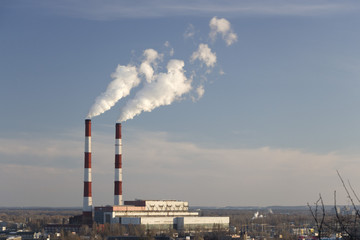 The pipe of the plant emits harmful substances into the atmosphere. Close-up on a sky background