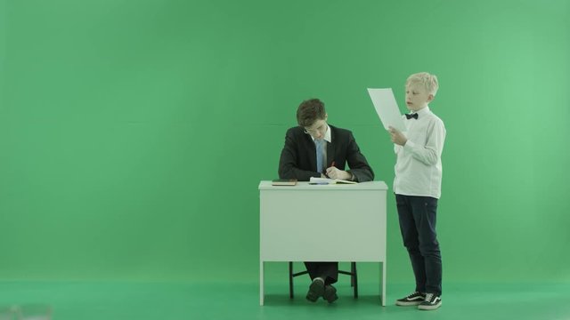 a student reading something to the teacher on the green screen
