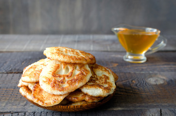 Russian-style fritters and honey on dark wooden background. Empty space