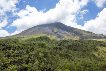 Fototapeta na wymiar Arenal Volcano in Costa Rica with its peak shrouded in light clouds