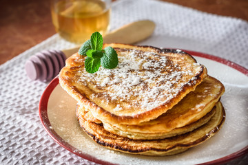 Pancakes with honey for breakfast on kitchen table	