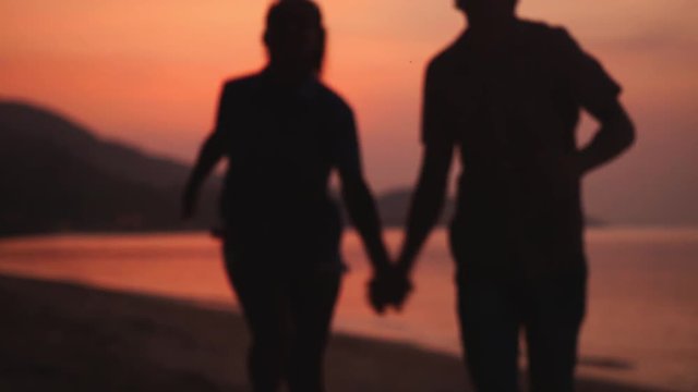 Happy couple run on the beach to the camera during amazing orange sunset holding hands. slow motion. 1920x1080