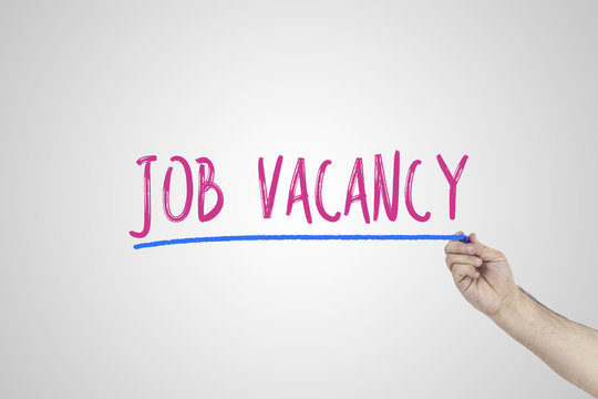 Human's hand writing Job vacancy on whiteboard.