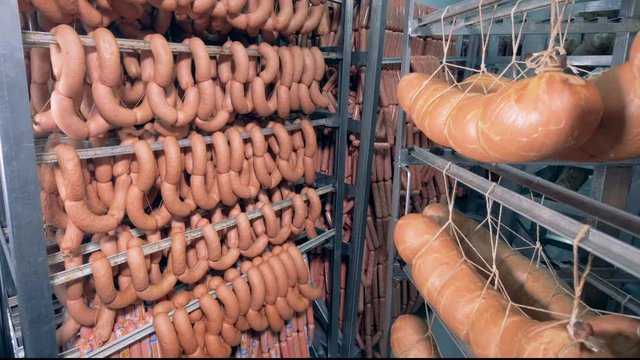 Bockwursts, ham and sausages are hanging on metal shelves at meet processing plant.