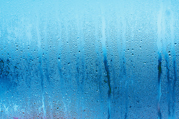 Blue background of natural water condensation, window glass with high air strong humidity, large drops drip. Collecting and streaming down - obrazy, fototapety, plakaty