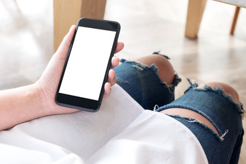 Mockup image of woman's hand holding black mobile phone with blank white desktop screen in cafe