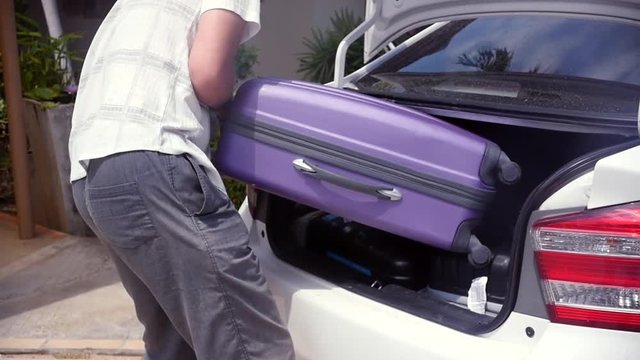 The man puts the third big heavy suitcase with things in the trunk of the car. slow motion, 1920x1080, full hd