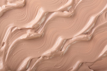 Beige liquid foundation makeup as a background. Top view. Flat lay pattern