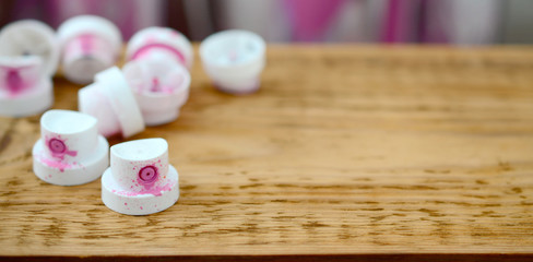 The soiled pink nozzles from the paint sprayer lies on a wooden plank on a background of a many...