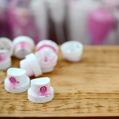 The soiled pink nozzles from the paint sprayer lies on a wooden plank on a background of a many dirty spray cans © mehaniq41