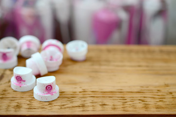 The soiled pink nozzles from the paint sprayer lies on a wooden plank on a background of a many...