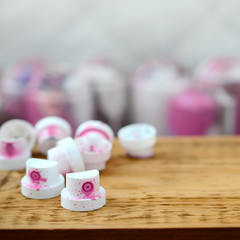 The soiled pink nozzles from the paint sprayer lies on a wooden plank on a background of a many...