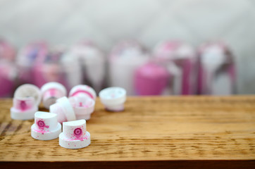 The soiled pink nozzles from the paint sprayer lies on a wooden plank on a background of a many...