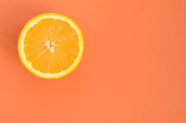 Top view of a one orange fruit slice on bright background in orange color. A saturated citrus texture image