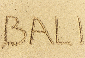 The inscription on the sand of Bali. Vacation time, beach holidays.