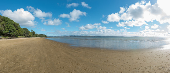 A deserted stretch of beach on a bright day under blue cloudy skies