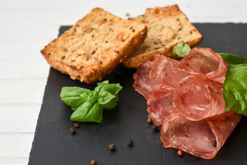 Salami smoked sausage slices basil leaves, peppercorns and bread