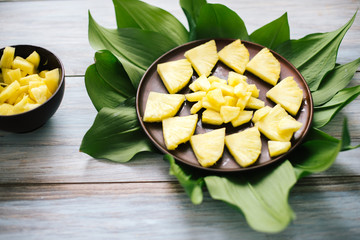 Sliced fresh pineapple in a bowl on the leaves