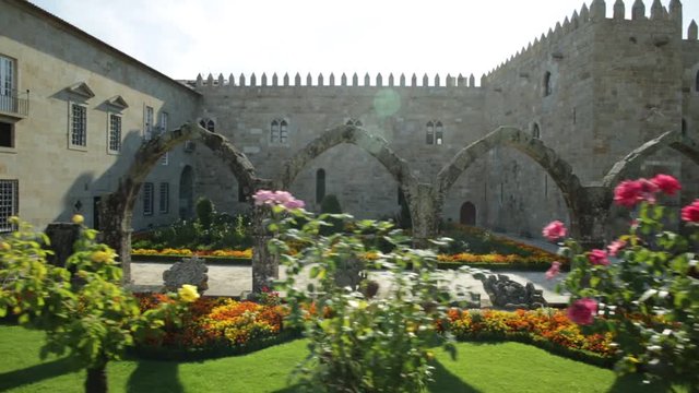 Beautiful view of architectural complex with flowery public garden outdoor of Episcopal Palace with medieval arcade in Praca do Municipio, Braga, north Portugal. Sunny day in blue sky.