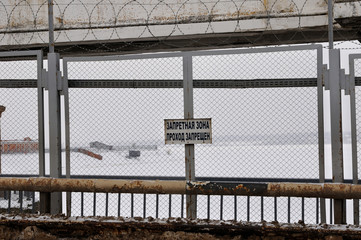 prohibited area no entry / A sign ‘Prohibited area. No entry’ on the fence of Uglich hydroelectric power station, frozen river and snow covered banks are on the background, Yaroslavl region