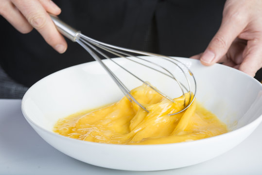 Cocinero batiendo huevo con un batidor de varillas 