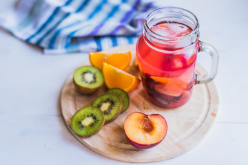 Iced red fruit tea in a glass and fresh tropical fruits on a wooden tray