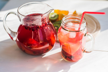 Cold lemonade with cranberries in a jug on the table and sliced fruit - a concept of relaxation and freshness