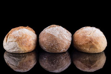 three freshly baked homemade artisan breads on black glossy table