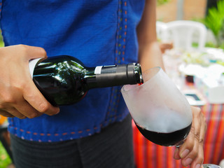 Closeup of woman pouring red wine into glass.